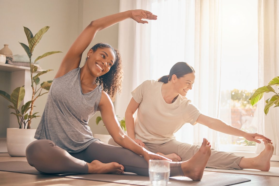 Two friends stretching and smiling in a bright living room in soft morning light